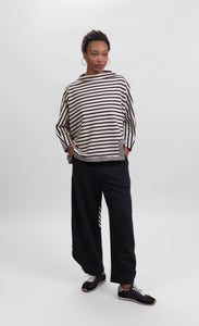 Front full body view of a woman wearing the alembika urban striped top and the alembike urban french terry punto pant. The wide pant is black.