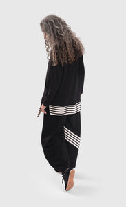Back full body view of a woman wearing the alembika urban black top and the alembika urban french terry punto pant. The wide pant is black with a black and white striped detailing on the back of the bottom of the right leg. 