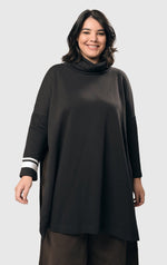 Load image into Gallery viewer, Front view of a woman wearing the alembika urban ribbon cowl neck tunic top in black. This tunic has deep side slits, a cowl neck, and long sleeves with two white stripes on the right arm.
