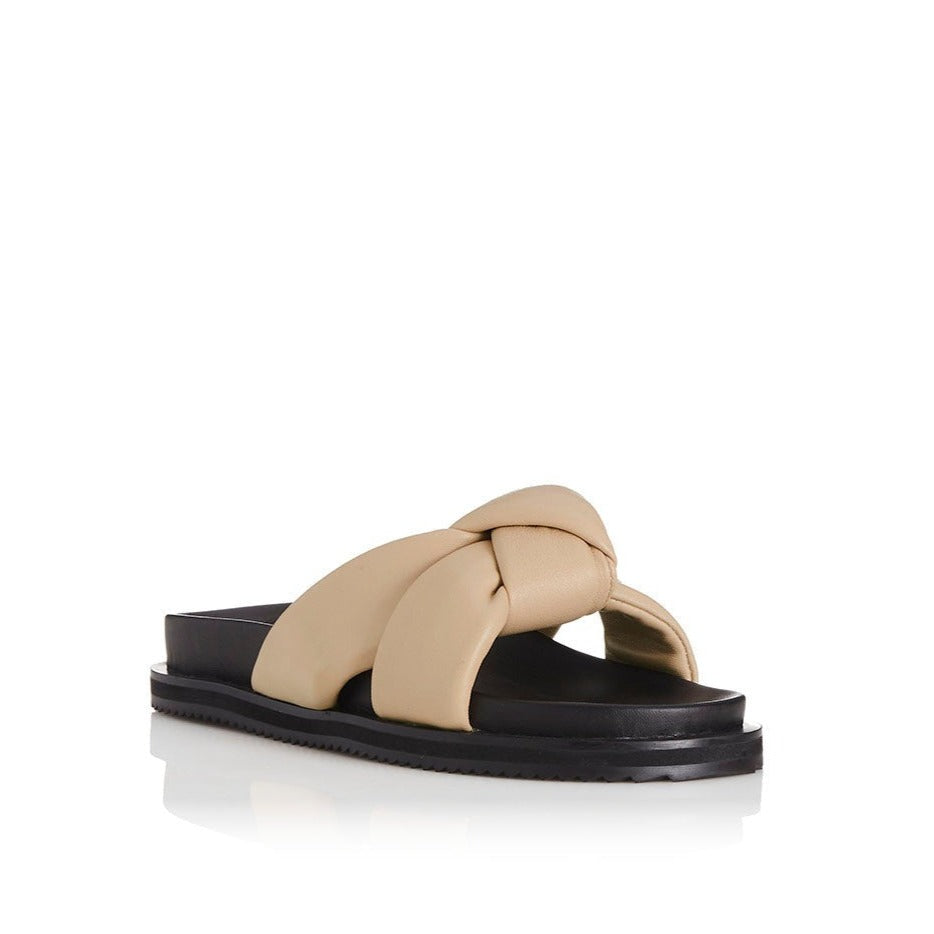 outer front side view of the alias mae sofia sandal. This slip on sandal has a beige natural colored puffer, leather double strap that comes together with a single knot in the front. 