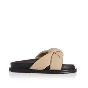 outer side view of the alias mae sofia sandal. This slip on sandal has a beige natural colored puffer, leather double strap that comes together with a single knot in the front. 