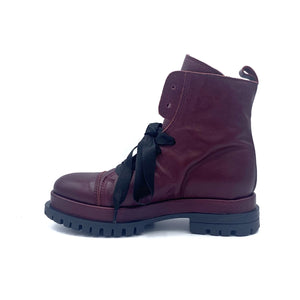 Inner side view of the all black ankle tie camper boot. This boot has a lug/combat boot look with wide black laces and an ankle length shaft. These boots are wine colored.