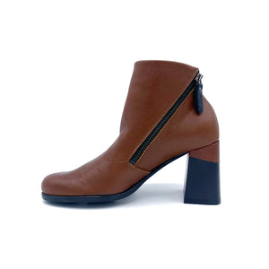 inner side view of the all black double zip hi bootie. This bootie is brown/orange colored. It has a zipper on the inner side and the leather color covers up a portion of the mid-height chunky black heel.