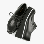 Load image into Gallery viewer, birdseye view of a pair of the all black footwear kiltie ox flatform. This shoe is black with a black platform sole and a lace up front. The sole and leather upper are separated by white piping around the shoe.
