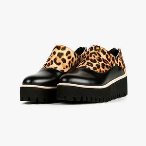 Outer side front view of a pair of the all black jungle spats flatform shoe. This shoe is black with a cheetah print on the upper. It has a zipper back and a black platform sole detailed with beige piping.