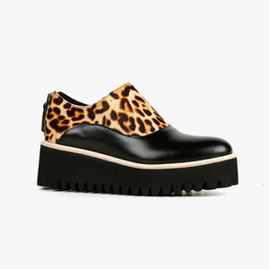 Outer side view of the all black jungle spats flatform shoe. This shoe is black with a cheetah print on the upper. It has a zipper back and a black platform sole detailed with beige piping.