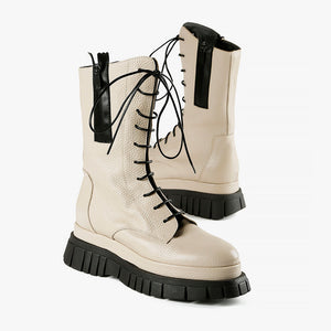 outer and inner side view of a pair of the all black lester lace lugg. This boot is ivory colored and has black laces, a black lugg sole, and a black outer zipper.