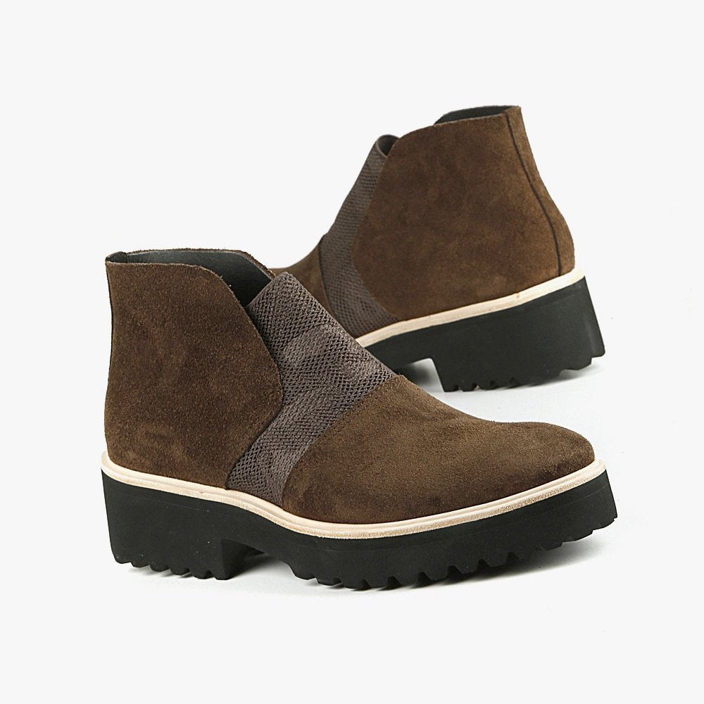 Outer and inner view of a pair of the all black nu banded bootie in brown. This ankle length bootie has a suede upper with an elastic camouflage inlet. The lugg sole is black with white piping.
