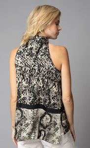 Back, top half view of a woman wearing the lola & sophie border animal print halter top. This sleeveless top has a high halter neck and a mix of two different snake skin prints separated by a black border that runs horizontally across the waist. There is also a short zipper on the back of the neck.