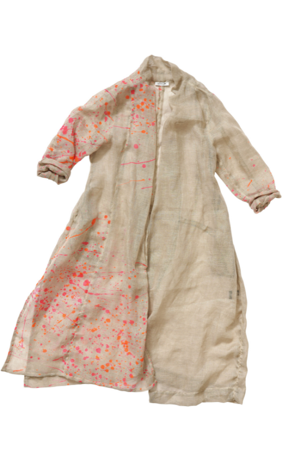 front view of the banana blue bright flax splash print duster. This duster is flax/beige colored with pink and orange splatter paint print. This duster goes down to the knees, has long sleeves, a straight fit, and a short stand collar.