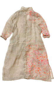Back view of the banana blue bright flax splash print duster. This duster is flax/beige colored with pink and orange splatter paint print. This duster goes down to the knees, has long sleeves, a straight fit, and a short stand collar.