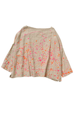Load image into Gallery viewer, Front  view of a woman wearing the banana blue bright flax splash top. This top is flax colored with a pink and orange splatter painted print appearance and a boxy silhouette. This top also has long sleeves and a boat neck.
