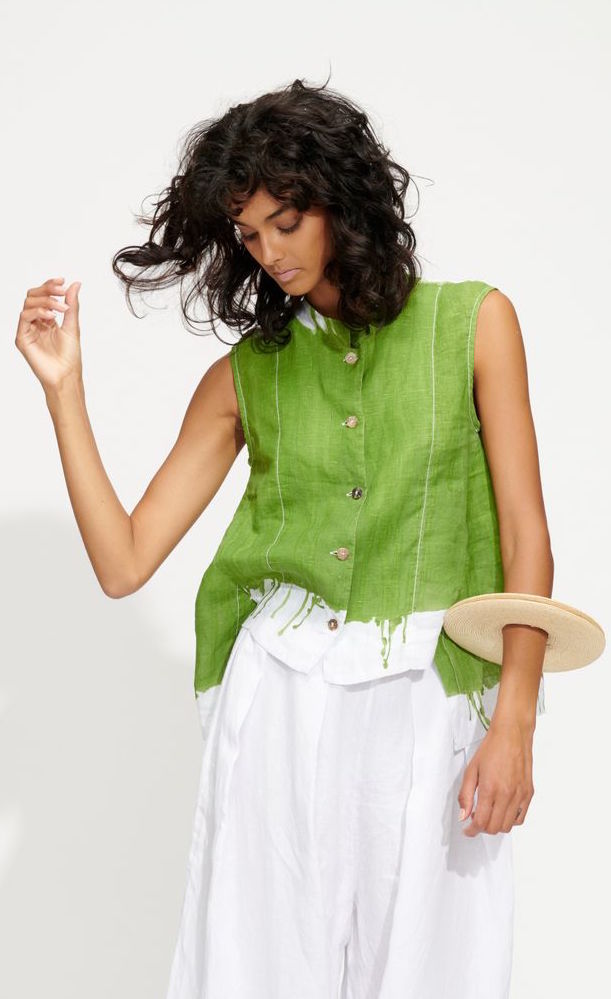 Front top half view of a woman wearing the banana blue green drip sleeveless shirt. This shirt has a button down front, a stand collar, and is dyed green with paint drippings on the bottom.