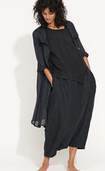 Load image into Gallery viewer, Front full body view of a woman wearing the banana blue solid navy splash duster. This duster is a dark navy that looks black. Under the duster the model is wearing a matching top and bottom. The duster has long sleeves, layered collar, and a pleated seam detail.

