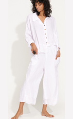 Load image into Gallery viewer, front full body view of a woman wearing the banana blue solid white pant with a white shirt. This pant has two front pockets and a wide cropped cut.
