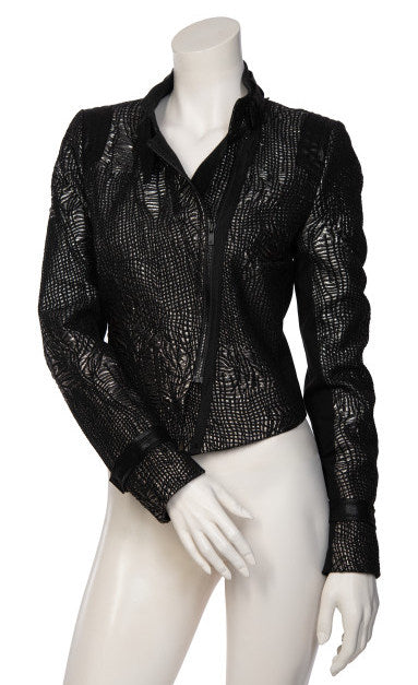 Front view of the beate heymann carbon jacket. This jacket is black with a cracked gold print all over it. The jacket is short with long sleeves, and off-center zipper, and a notched collar.