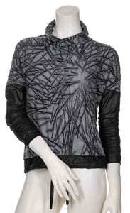 Front view of the beate heymann abstract top. This top is grey with black scribbles all over it. The top also has a mock neck, drop shoulder sleeves and black pleather detailing on the sleeves and hem.