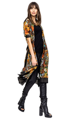 Load image into Gallery viewer, front full body view of a woman wearing open the beate heymann colorful blouse dress. This dress has elbow length sleeves and sits at the knees. The dress has a multicolor floral print with black chevron mixed in. The hem has black striped detailing. The dress also has a black striped tie belt at the waist.
