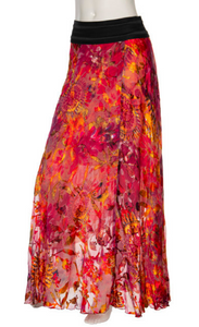 Front bottom half view of a mannequin wearing the beate heymann fuchsia firewall skirt. This skirt has a mixed print of pink, red, and orange. It is slim but relaxed and flowy. The skirt ends at the ankle.