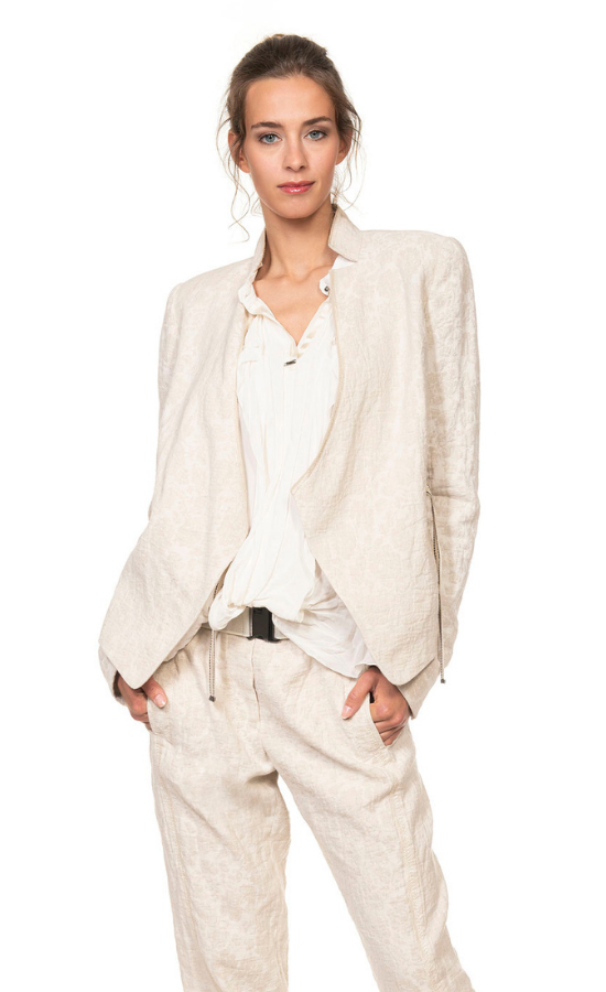 Front top half view of a woman wearing beige pants and the beate heymann jacquard wrap jacket. This jacket is beige too and being worn open over a white blouse. The jacket has a short stand collar and long sleeves