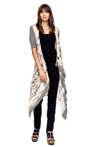 Front full body view of a woman wearing black pants, a black tank, and the Beate Heymann Linen Wrap/Cardi. This wrap is cream colored with floral print. The sleeves and hem are black and white striped. 