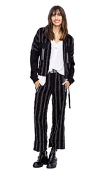 Load image into Gallery viewer, Front, full body view of a woman wearing the Beate Heymann Striped Cullote Pants, a white top, and the Beate Heymann Stripped Jacket. This jacket is black with white stripes. The sleeves are solid black and the front has two patch, solid black pockets with a single white stripe on them. The jacket has a zip up front and belt near the bottom.
