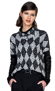 Front top half view of a woman wearing the beate heymann knit rhombus top. This top has a black and white diamond/rhombus print with a mock neck and drop shoulder leather-looking black long sleeves.