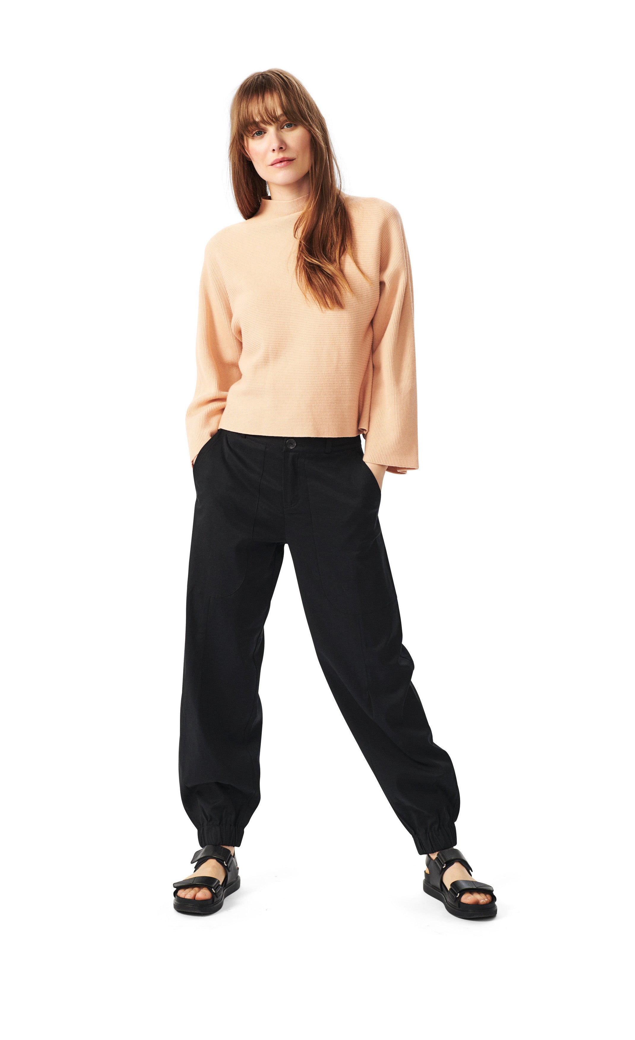Front full body view of a woman wearing the bitte kai rand botanic twill elastic pant. This pant is black and has a relaxed fit with an elastic hem.