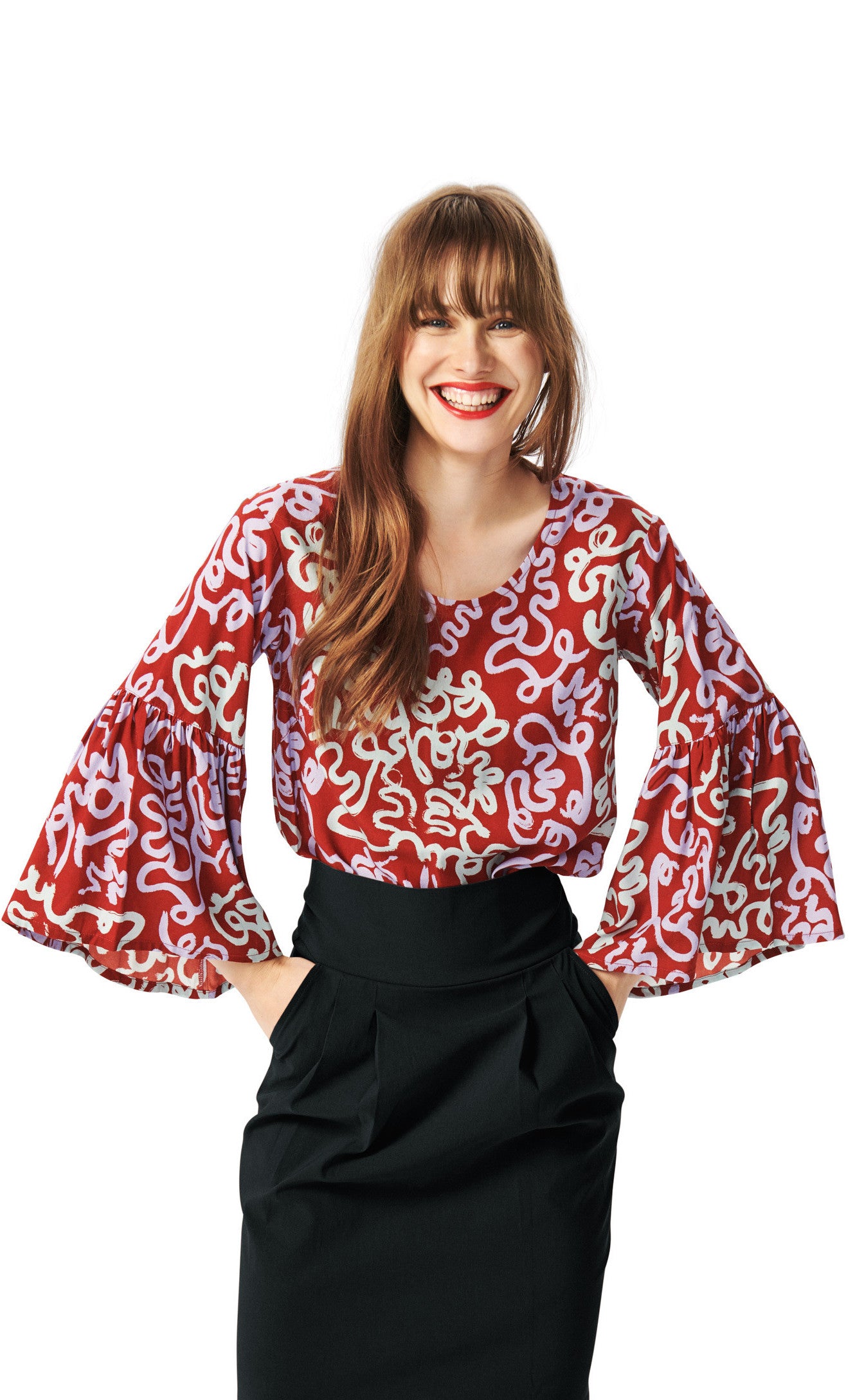 Front top half view of a woman wearing the bitte kai rand dancing brush blouse. This top is red with a pastel purple and pastel green swirl print. The top has a round neck and ruffled sleeves.
