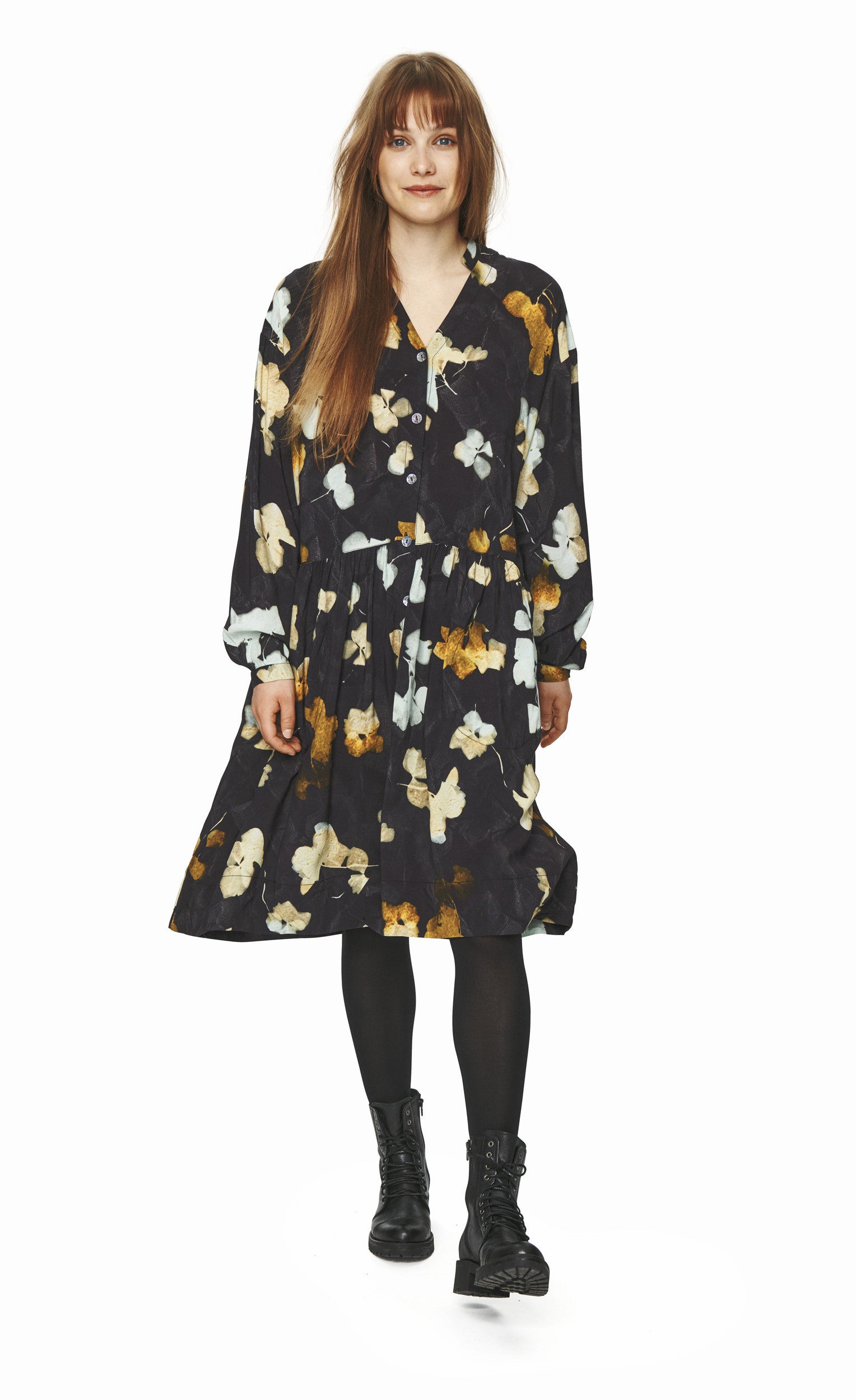 Front full body view of a woman wearing the bitte kai rand falling leaves dress. This dress is dark grey with mustard and light blue colored leaves all over. The dress is a button up with long sleeves and a seam at the waist.