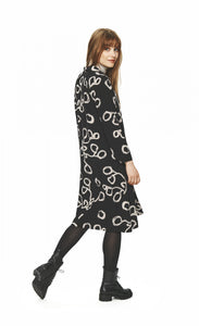 Back full body view of a woman wearing tights and the bitte kai rand lunaria shirt dress. This dress is black with long sleeves and a cream squiggle print.