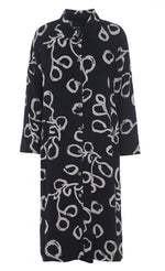 Load image into Gallery viewer, Front view of the bitte kai rand lunaria shirt dress. This dress is a black button down dress with long sleeves and a cream squiggle print.
