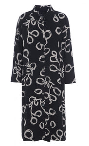 Front view of the bitte kai rand lunaria shirt dress. This dress is a black button down dress with long sleeves and a cream squiggle print.