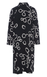 Load image into Gallery viewer, Back view of the bitte kai rand lunaria shirt dress. This dress is black with long sleeves and a cream squiggle print.
