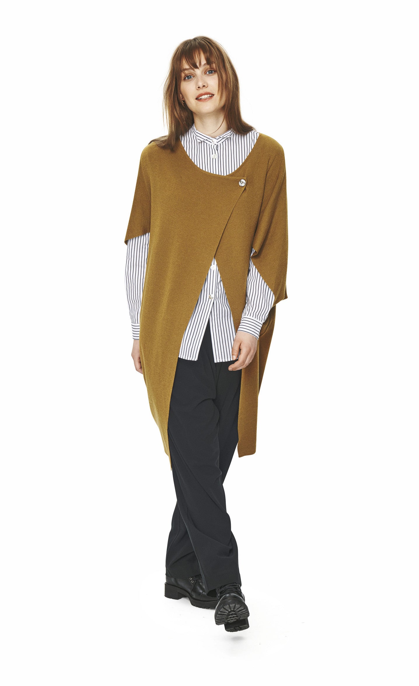Front full body view of a woman wearing black pants, a black and white shirt and the bitte kai rand merino mix cape in the color mustard. This cape has a double button cross body closure near the neck and two wide elbow length sleeves.
