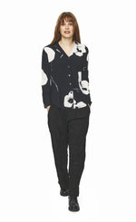 Load image into Gallery viewer, Front full body view of a woman wearing black pants and the bitte kai rand oki flower shirt. This shirt is black with large white flowers. It has a button down front, long sleeves, and a form-fitting silhouette.
