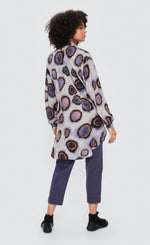 Load image into Gallery viewer, Back full body view of a woman wearing the bitte kai rand sea shirt. This purple/grey shirt has circular print on it in purple and orange. The shirt has a button down front and a curved hem.
