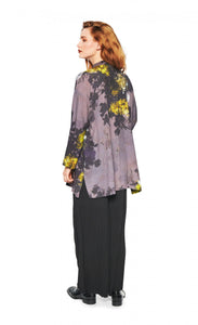 Back full body view of a woman wearing the bitte kai rand grey wilderness shirt. This shirt is grey with a mix of yellow, ice blue, and black flowers. The shirt has a button up front.