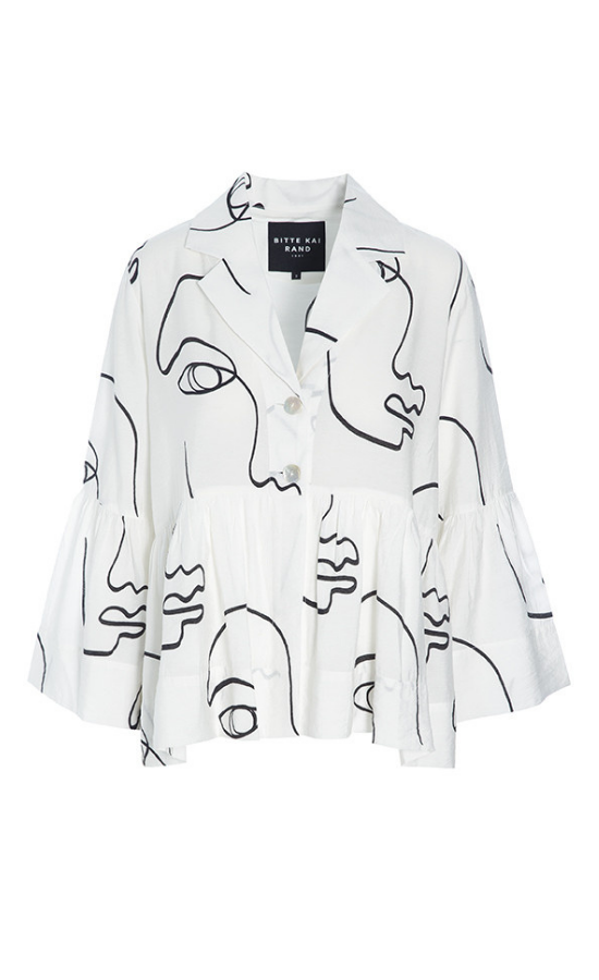 Front view of the bitte kai rand sketch viscose shirt jacket. This shirt is white with black sketch faces on it. It has a two button up front, a notched collar, long sleeves with ruffles, and a ruffles on the bottom half of the top.