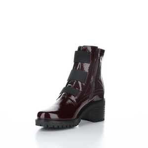 Inner front side view of the Bos & Co patent leather boot in the color bordeaux/bordo. This boot has a chunky mid-heel and 3 elastic bands on the front.