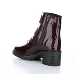 Load image into Gallery viewer, Inner back side view of the Bos &amp; Co patent leather boot in the color bordeaux/bordo. This boot has a chunky mid-heel and 3 elastic bands on the front.
