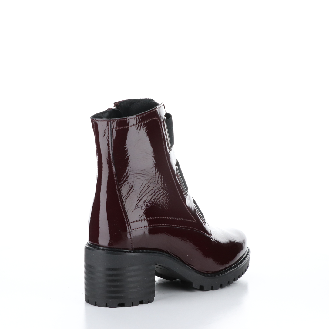 Outer back side view of the Bos & Co patent leather boot in the color bordeaux/bordo. This boot has a chunky mid-heel and 3 elastic bands on the front.
