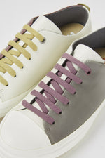 Load image into Gallery viewer, Closeup top view of a pair of the camper twins sneaker. The left sneaker is white on one side and grey on the other with purple laces. The right foot is white on one side and purple on the other side with mustard laces.

