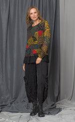 Load image into Gallery viewer, front full body view of a woman wearing the chalet andrea patch top. This top has long sleeves, a round neck, and a relaxed fit. The top has a mix of yellow, brown, and red print.
