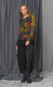 front full body view of a woman wearing the chalet andrea patch top. This top has long sleeves, a round neck, and a relaxed fit. The top has a mix of yellow, brown, and red print.