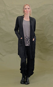 Front full body view of a woman wearing the chalet black cleon cardigan. This long cardigan has long sleeves, a draped open front, and two front draped pockets.