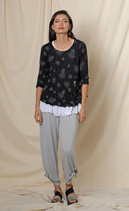 Front full body view of a woman wearing the chalet gizel top. This top is black with white flowers. It has 3/4 length sleeves and a scoop neck.
