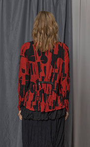 back top half view of the chalet gizel top. This top is red with a black retro print. It has long sleeves, crinkled fabric, and a zippered back that provides shape around the waist.