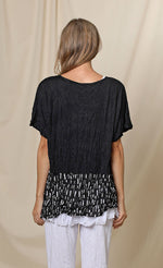 Load image into Gallery viewer, Back top half view of a woman wearing the chalet josephine top. This short sleeve top is black with a black and white printed band at the bottom.
