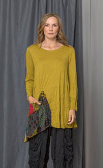 Load image into Gallery viewer, Front top half view of a woman wearing the chalet katya top in the color medallion (yellow). This top is a tunic with long sleeves, a round neck, and an asymmetrical hem.
